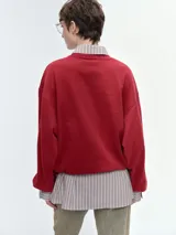 Buzo oversize de corte amplio y relajado, color rojo, con cuello redondo acanalado, mangas anchas y bajo regulable mediante elásticos.