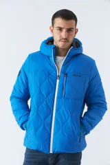 Campera de nylon azul con capucha, cierre frontal con cremallera, bolsillos laterales con cierre y logo de goma en el pecho.