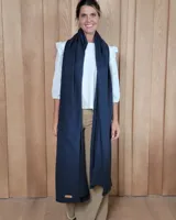 Bufandón de lana lambswool, de textura suave y liviana, con diseño liso y etiqueta de cuero en el extremo inferior.