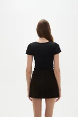 Falda mini de jean color marrón oscuro, con diseño de cinco bolsillos, cierre frontal con botón y costuras a tono.
