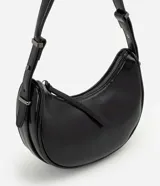 Cartera tipo baguette Satinato color negro, de estructura curva y acabado charolado uniforme. Cuenta con cierre superior y asa ajustable con hebilla metálica.