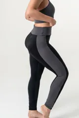Calza deportiva de tiro alto con cintura elástica reforzada. Presenta un diseño bicolor que combina paneles laterales y faja con estampado animal print en tonos coral y turquesa sobre una base negra.