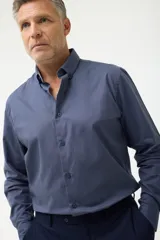 Camisa de vestir azul con cuello abotonado, corte clásico y mangas largas.