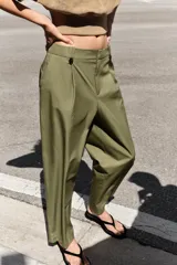 Pantalón de tiro alto con corte recto, bolsillos delanteros y detalle de pinzas con botones en la cintura. Cuenta con cierre frontal de cremallera y gancho metálico.