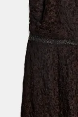 Vestido midi de encaje color marrón oscuro, con cuello halter ajustable con lazadas, detalle de cintura con aplicación de brillos y espalda descubierta. El bajo tiene un acabado en línea evasé.