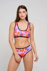 Bombacha de bikini tipo culotte tiro alto, con laterales anchos y ribete en color negro. Presenta un diseño estampado floral en tonos rosados, naranjas y azules.
