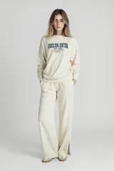 Buzo color crudo con estampado de texto en azul y violeta. Corte holgado y mangas largas.