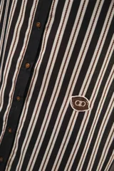 Vestido camisero corto, con cuello mao, botones a tono y parche con logo en el frente. Diseño a rayas verticales negras y blancas.