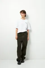 Remera negra de corte oversize con cuello redondo y manga corta. Presenta un pequeño estampado dorado en el pecho con la frase "love earth" y un símbolo de hojas.