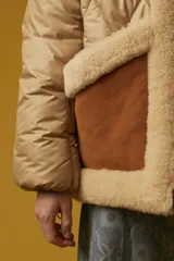 Campera puffer color beige con diseño acolchado de rombos, cuello y solapa de sherpa color crema, cierre frontal con cremallera dorada, bolsillos laterales con solapa marrón y puños elásticos.