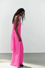 Vestido largo fucsia de cuello halter, espalda descubierta y cierre lateral con cremallera oculta en costura.