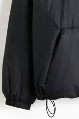 Campera acolchada de corte holgado, repelente al agua y rompevientos. Cuenta con capucha ajustable con cordón, cierre frontal, hombros caídos, puños elásticos y bolsillos delanteros.