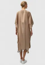 Túnica color beige de algodón, holgada, con cuello en V profundo, detalle de borlas y encaje en el ruedo.