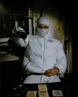 Campera puffer negra con capucha, cierre frontal con botones a presión y cordones ajustables en la cintura. Presenta un estampado gráfico circular con el número 27 en el pecho.