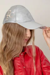 Gorra tipo baseball confeccionada en cuero ovino italiano color dorado metalizado, con bordado del monograma PEC en el lateral.