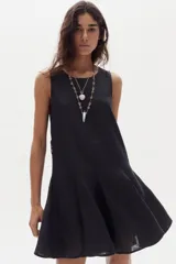 Vestido corto de lino negro, sin mangas, con cuello redondo y diseño evasé con godets en el ruedo que aportan movimiento.