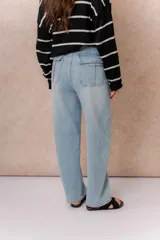 Jean wide leg de tiro alto en denim color celeste claro. Presenta un diseño de cinco bolsillos, destacándose los bolsillos traseros con solapa y detalle de marca metálica. Posee cierre frontal con botón y ruedo recto.