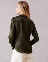 Camisa de satén color verde oliva, con cuello clásico, cierre frontal con botones metálicos y mangas largas con puños abotonados.