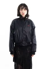 Campera bomber negra de tela satinada con bordado rojo en el pecho. Es reversible.