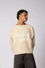 Buzo oversize de corte boxy, confeccionado en algodón rústico de alto gramaje en color beige. Presenta cuello redondo con borde crudo, mangas largas y una estampa frontal con el texto VCP delimitado por líneas horizontales blancas.