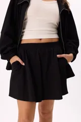 Conjunto deportivo compuesto por un buzo con cierre frontal y una falda corta, confeccionados en algodón liviano. El buzo presenta cuello alto, mangas largas con puños elásticos y un diseño holgado.