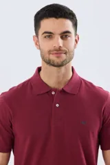 Remera polo lisa de piqué en color bordó, con cuello camisero, cierre frontal con botones y mangas cortas.