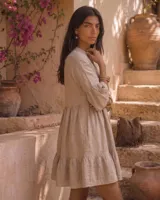 Vestido corto verde militar de lino, con cuello mao, escote en V con botones, mangas tres cuartos acampanadas con volados y falda con volado en el ruedo.