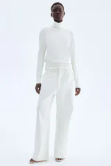 Polera blanca de punto fino, con cuello alto, mangas largas y bajo recto. Cuello, puños y bajo acanalados.