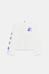 Remera de manga larga y corte oversize, color blanco, con cuello redondo. Presenta un estampado gráfico en color azul en el pecho y a lo largo de la manga derecha.