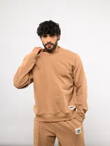 Buzo de cuello redondo color tostado, confeccionado en felpa suave, con diseño de mangas raglán y etiqueta con logo de la marca en el frente.