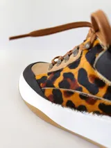 Championes deportivos de cuero con estampado animal print, cordones marrones y suela blanca con base color caramelo.