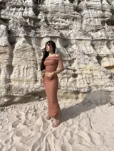 Conjunto de dos piezas compuesto por un top de hombros descubiertos y una falda larga de corte recto con tajo lateral, confeccionado en tela bambula elastizada color camel.