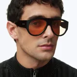 Lentes de sol estilo aviador con montura oversized de color negro y lentes polarizados en tono naranja. Presentan un diseño retro con líneas limpias y protección UV400.