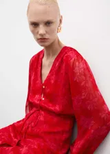 Vestido midi de tejido fluido en color rojo con estampado floral tono sobre tono. Presenta escote en pico, cierre frontal de botones ocultos, mangas largas con puños elásticos y nudo ajustable en la cintura. Incluye forro interior.