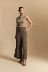 Pantalón ancho color tostado, de silueta fluida y cintura elastizada. Presenta una pretina ancha con botones metalizados irregulares.