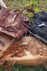 Bolso maxi de cuero marrón con textura croco, flecos laterales y botón de guampa. Tiene bolsillo interior y cierre metálico.