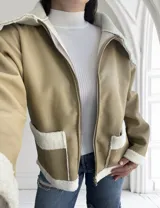 Campera color beige de ecocuero con interior de corderito blanco, cierre frontal con cremallera y bolsillos laterales.