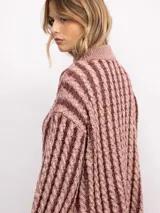 Sweater de punto con diseño de trenzas verticales, cuello alto y silueta oversize. Presenta un patrón bicolor en tonos azul y azul oscuro, con mangas largas y terminaciones en tejido acanalado.