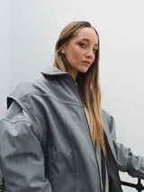 Campera gris con cierre frontal, cuello camisero y mangas largas con puños elásticos.