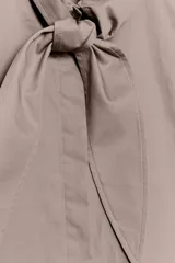 Camisa sin mangas confeccionada en algodón, con cuello redondo y detalle de lazada frontal. Presenta cierre frontal con botones ocultos por solapa y bajo redondeado.