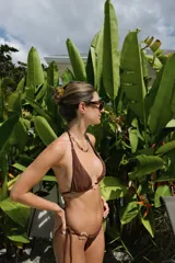 Top de bikini triangular negro con tirantes finos para atar al cuello y en la espalda, y detalle de argolla de resina carey en el centro.