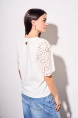 Remera de algodón peinado color negro, con mangas cortas de broderie con diseño calado y terminación festoneada. Presenta un corte oversize y cuello redondo.