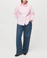 Camisa entallada de popelín de algodón en color rosado, con cuello camisero, manga larga y cierre frontal con botones ocultos bajo tapeta.