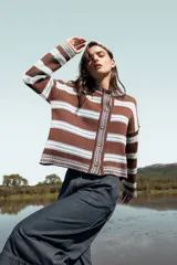 Cardigan de punto con diseño de rayas horizontales en tonos marrón y celeste. Presenta cierre frontal con botones, cuello redondo y corte boxy de silueta relajada.