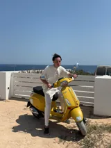 Remera marrón de corte holgado con estampado en la espalda que incluye la palabra "ITTAI" en blanco con líneas rojas y azules, la frase "AN IBIZA PRODUCE" y un texto más pequeño que dice "Ittai Stars Department Gallery - Ibiza Edition. If you're in Ibiza, 112 is not an option.".