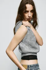 Jersey de punto gris jaspeado con cuello redondo y manga corta. Presenta detalles de encaje en los laterales.