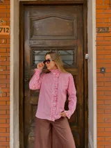 Camisa de manga larga con estampado de rayas verticales en color rojo y blanco. Presenta cuello alto con volados, cierre frontal con botones y detalles de volados en la solapa y en los puños.