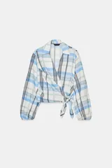Camisa de cuello solapa y escote en pico, con diseño de cuadros en tonos azules, blancos y verdes. Presenta cierre frontal cruzado con lazada lateral y mangas largas con puños elásticos.