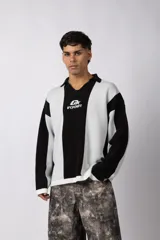 Sweater de punto con diseño a rayas verticales en color beige y blanco, de corte holgado y cuello polo abierto. Presenta un logo bordado en el centro del pecho.