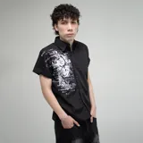 Camisa negra de manga corta con cuello, corte regular fit y estampado gráfico en blanco con tipografía gótica y un diseño central.